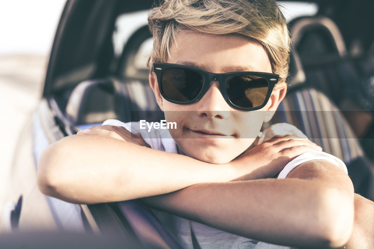 Boy wearing sunglasses sitting in car