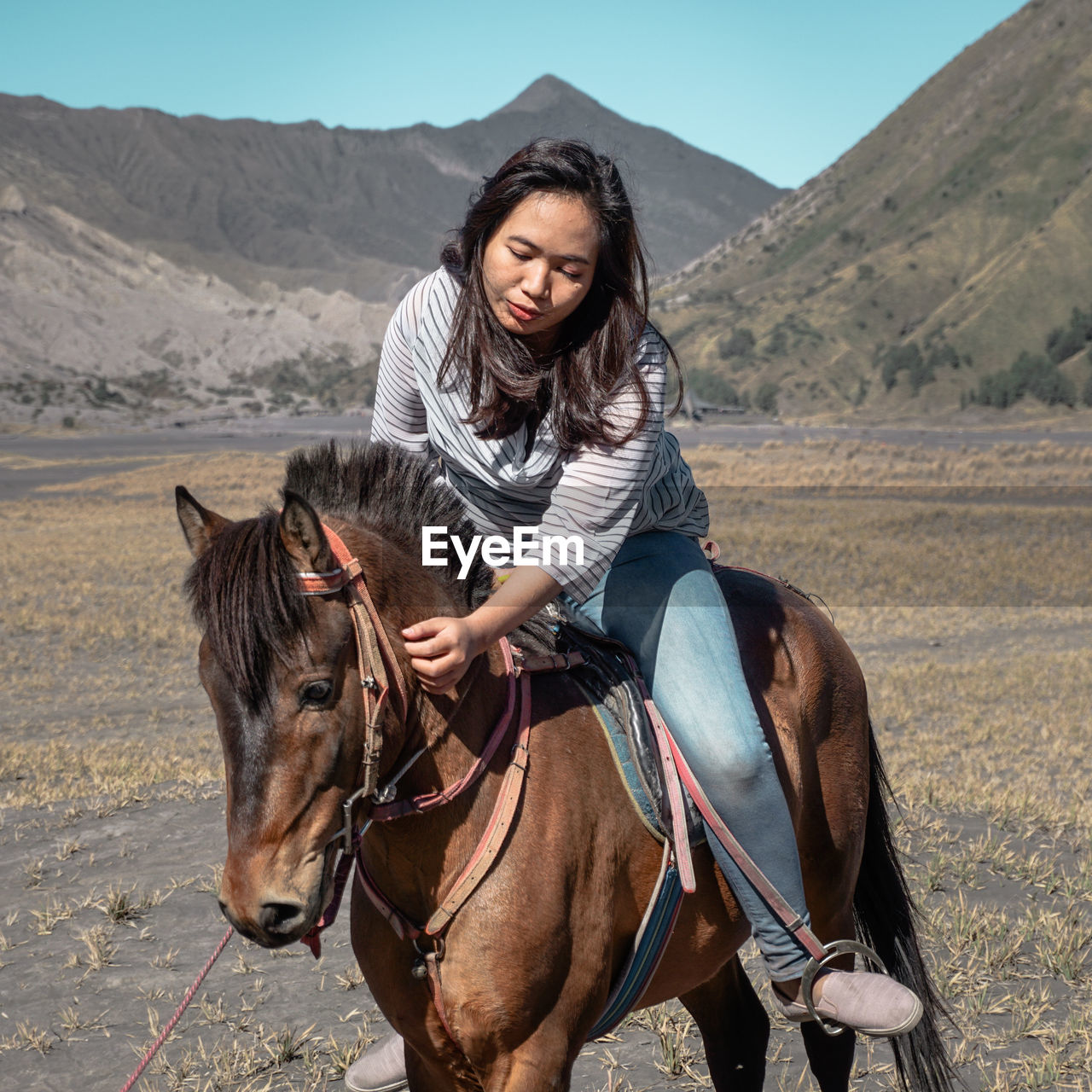 Woman riding horse on land against mountains