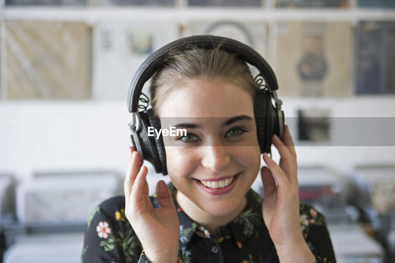 Smiling young woman listening to music in a record store