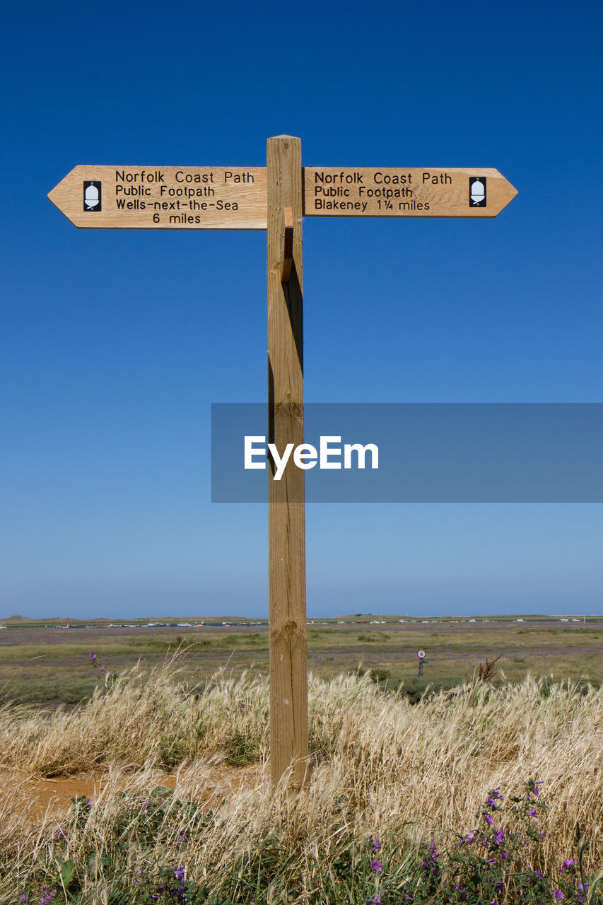 Information sign on field against clear blue sky