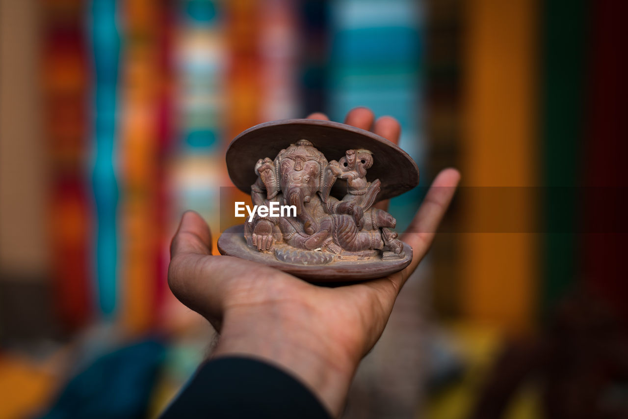 Close-up of cropped hand holding ganesha figurine