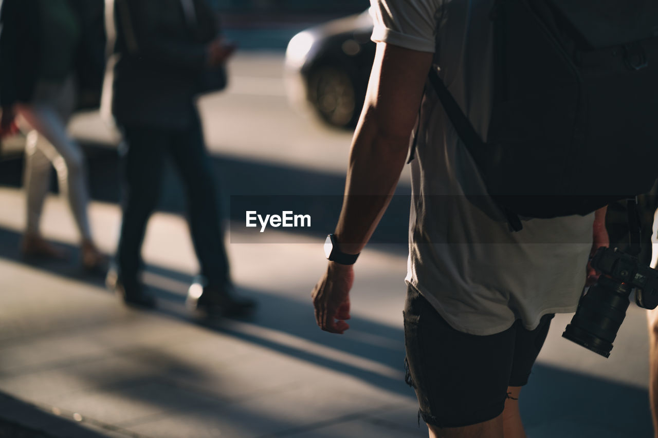 Low section of people walking on street in city