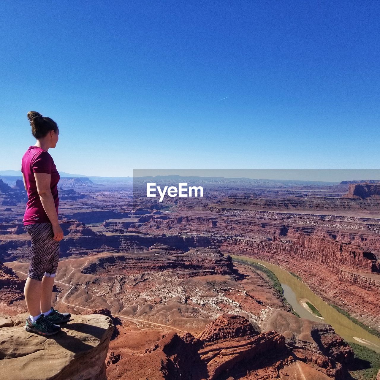 Women standing on rock against clear blue sky