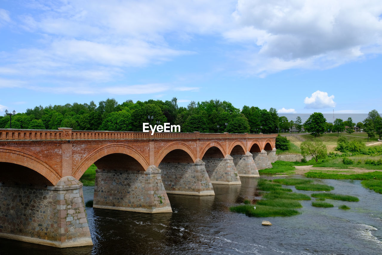 Arch bridge over river against sky