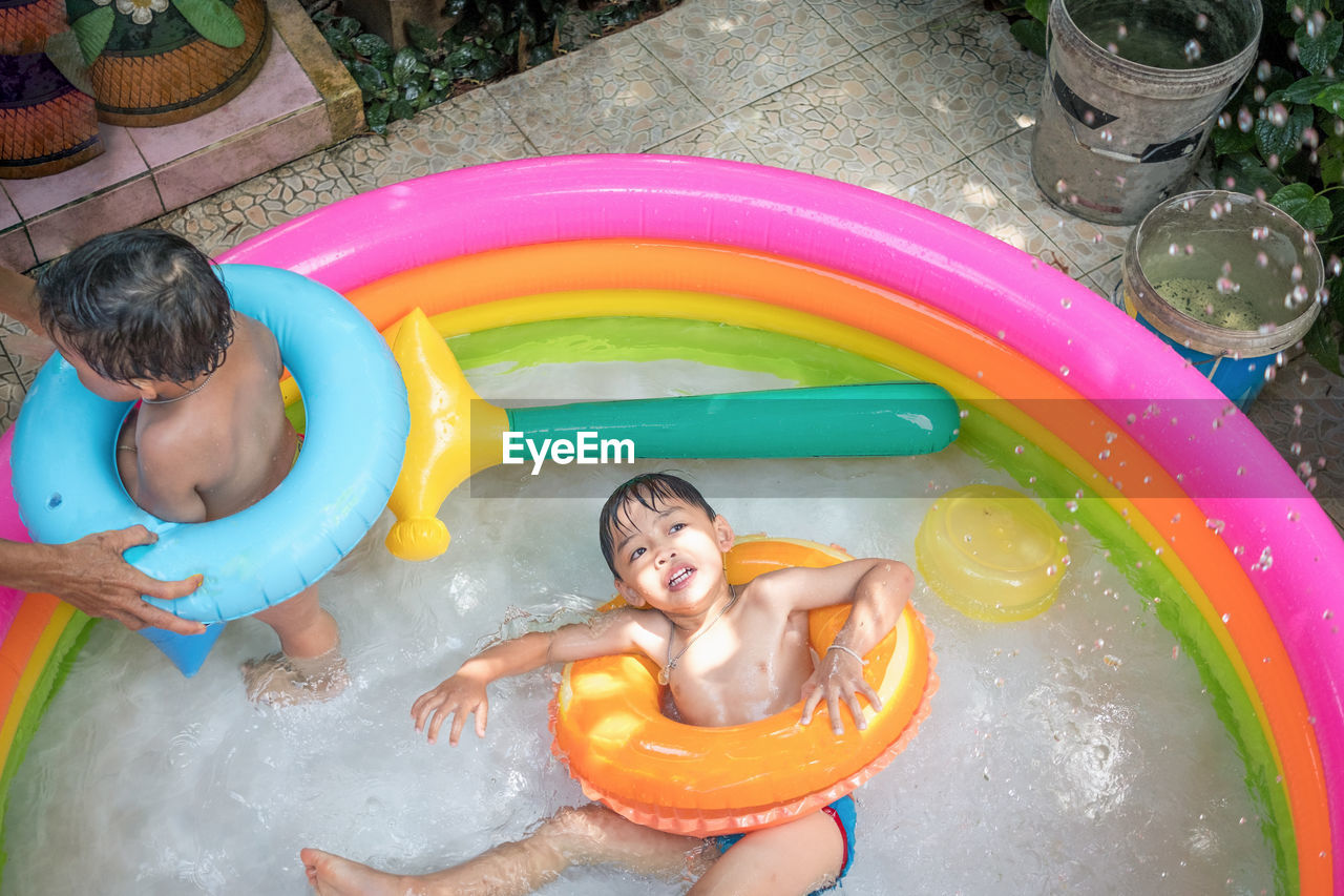 High angle view of siblings with parent in wading pool