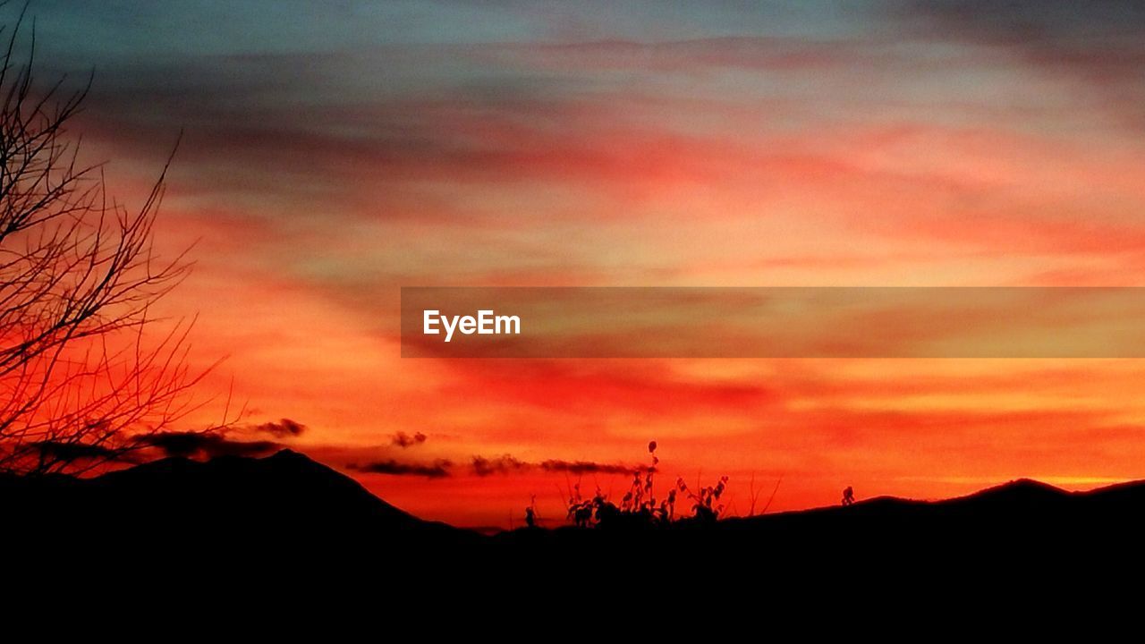 SCENIC VIEW OF SILHOUETTE MOUNTAIN AGAINST ORANGE SKY