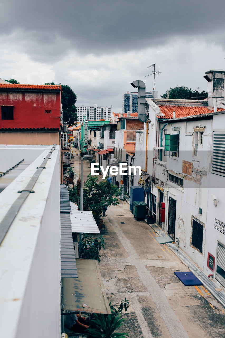 High angle view of street amidst buildings against cloudy sky