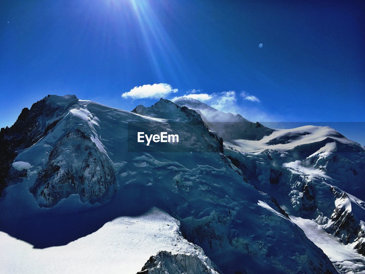 SCENIC VIEW OF SNOWCAPPED MOUNTAINS AGAINST BRIGHT SUN