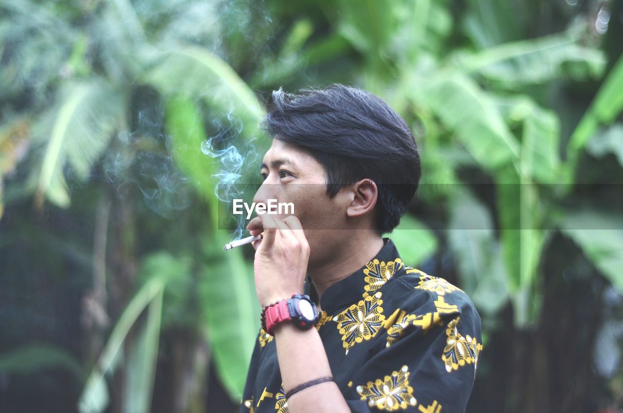 Portrait of young man smoking cigarette outdoors