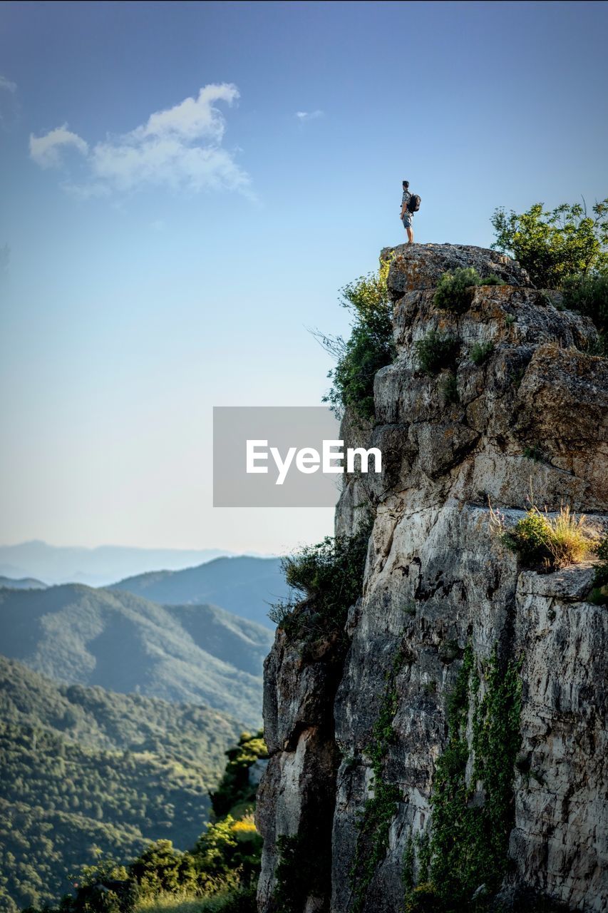 Scenic view of mountains against sky with man standing on rock