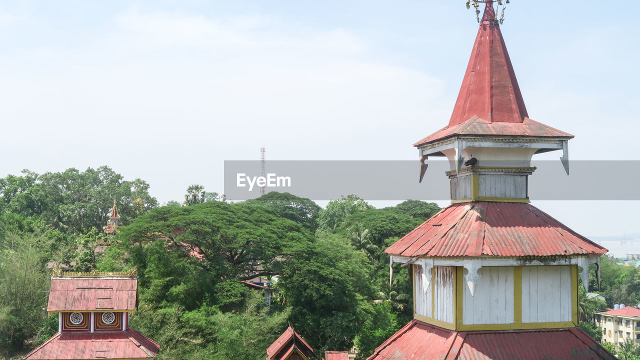 HIGH SECTION OF TRADITIONAL BUILDING BY TREES AGAINST SKY