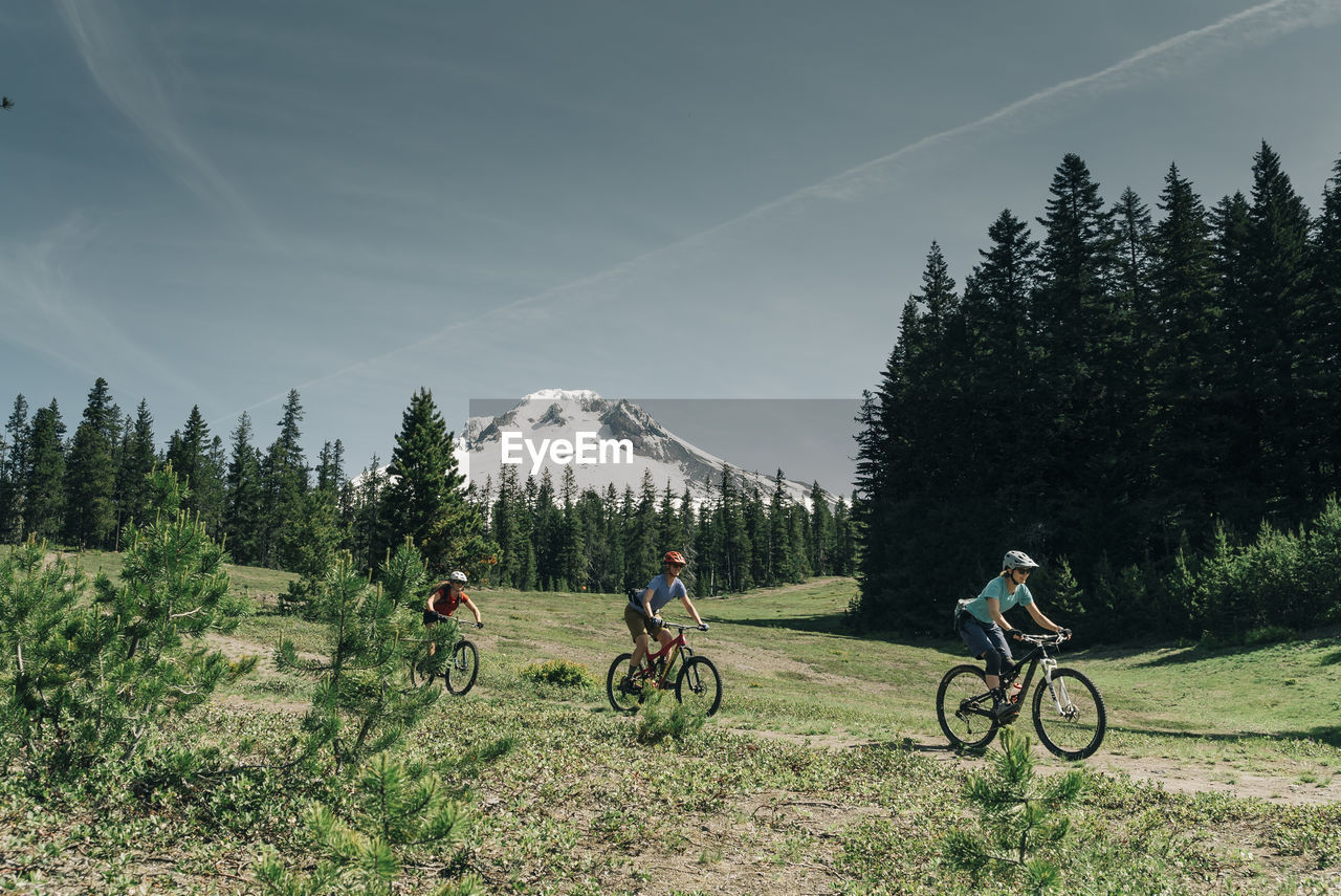 Threee women bike on a trail near mt. hood in oregon.