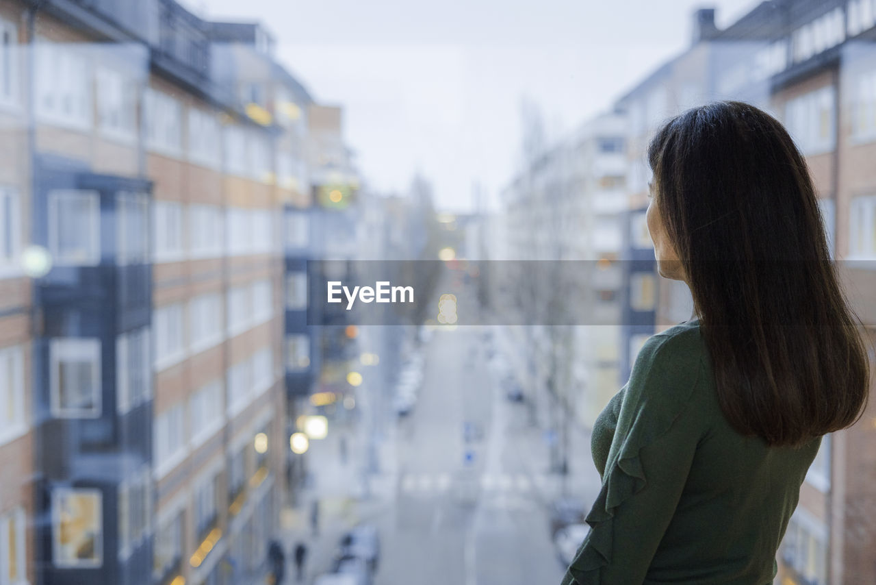 Woman looking through window at street