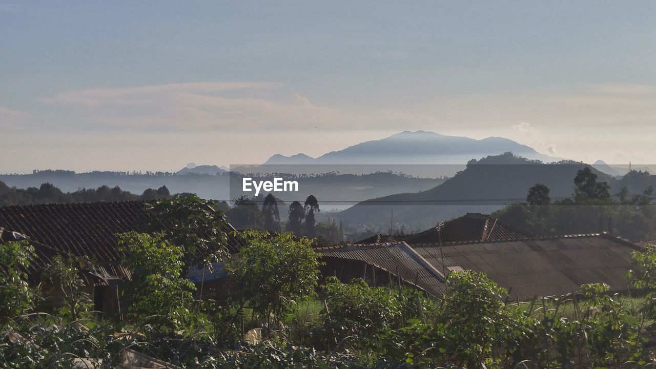 Houses on field by mountains against sky