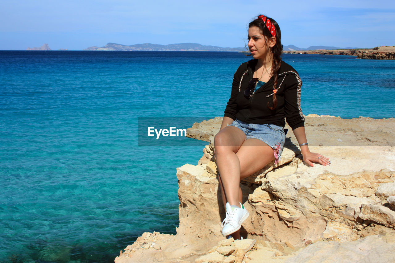 Girl in aummer at sea on the crazy cliff of formentera with crystal clear blue water in cala saona