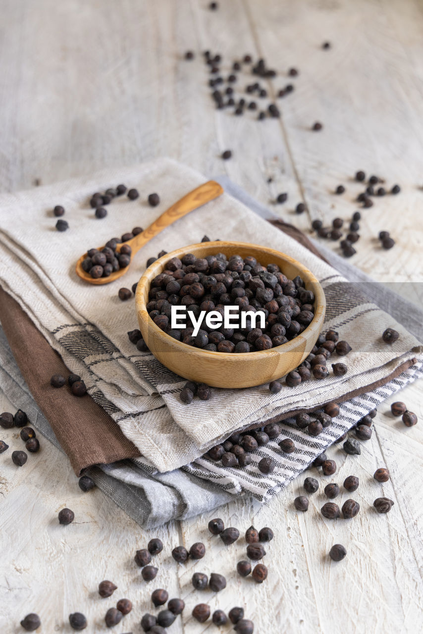 Wooden bowl of dry black chickpea from apulia and basilicata in italy with spoon on grey table 