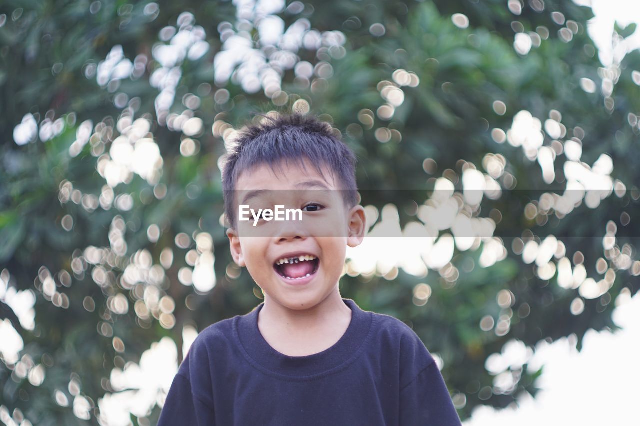 Portrait of cute boy against trees