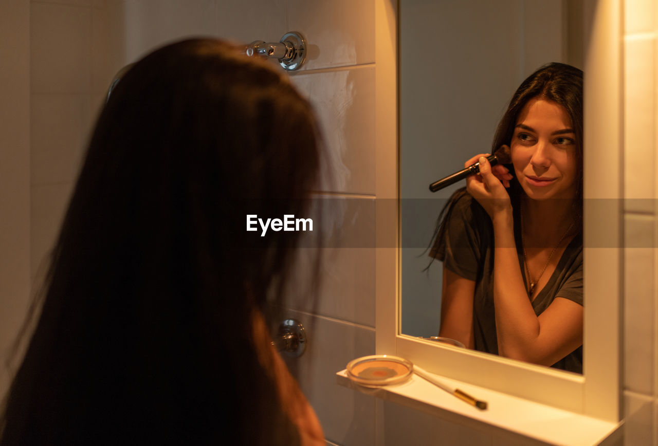 Young female doing makeup in bathroom