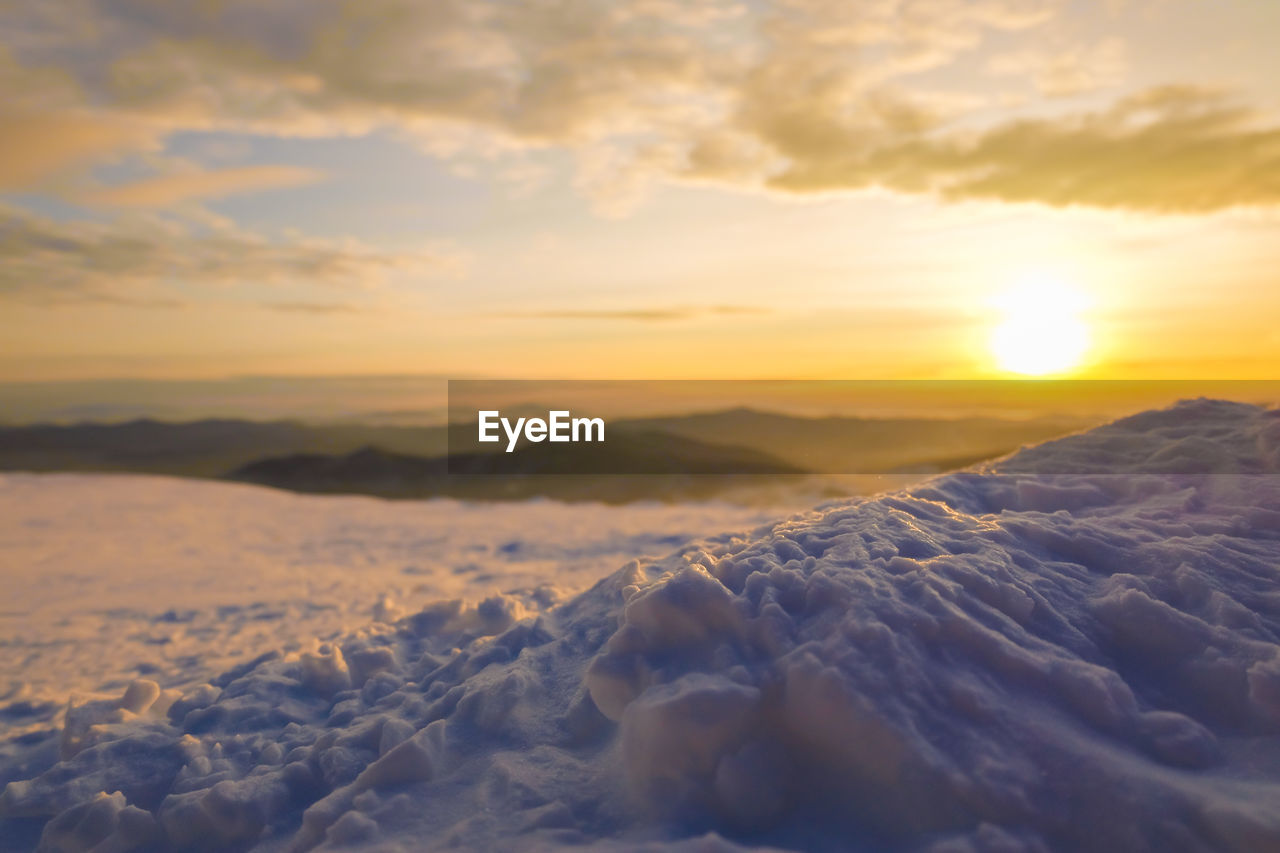 SCENIC VIEW OF SNOW COVERED LANDSCAPE AGAINST SKY DURING SUNSET