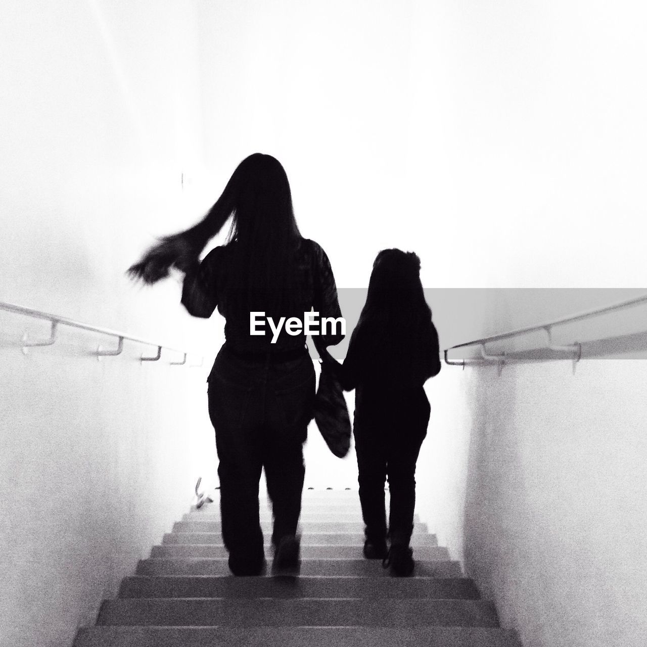 Silhouette of mother and daughter walking down stairs