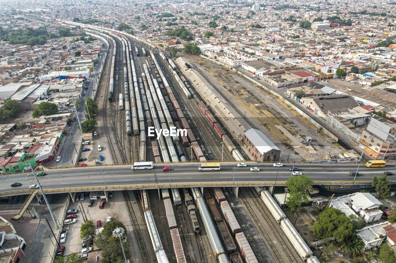 transportation, architecture, high angle view, metropolitan area, city, junction, mode of transportation, overpass, built structure, transport, aerial photography, track, road, building exterior, residential area, highway, traffic, aerial view, rail transportation, bird's-eye view, motor vehicle, cityscape, street, car, railroad track, public transport, public transportation, day, no people, land vehicle, nature, outdoors, freeway, train, road intersection, city life, elevated road, infrastructure, business, building, crossroad, multiple lane highway, residential district, city street, travel, lane, shunting yard, race track, business finance and industry, suburb, freight transportation, vehicle, industry