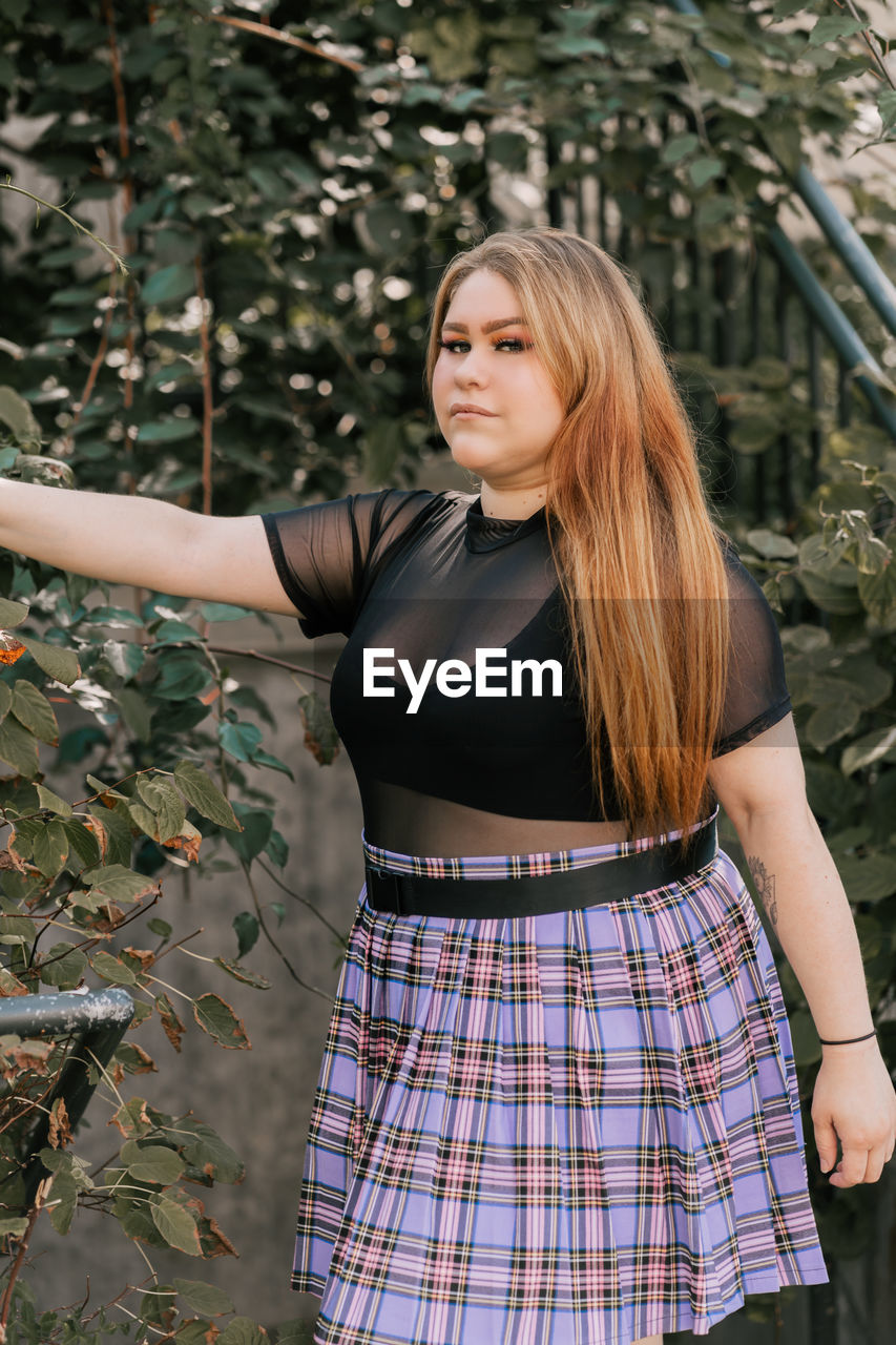 Beautiful young woman standing against plants