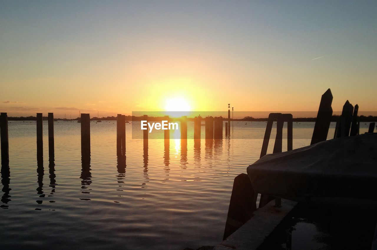 Silhouette pier over lake against sky during sunset