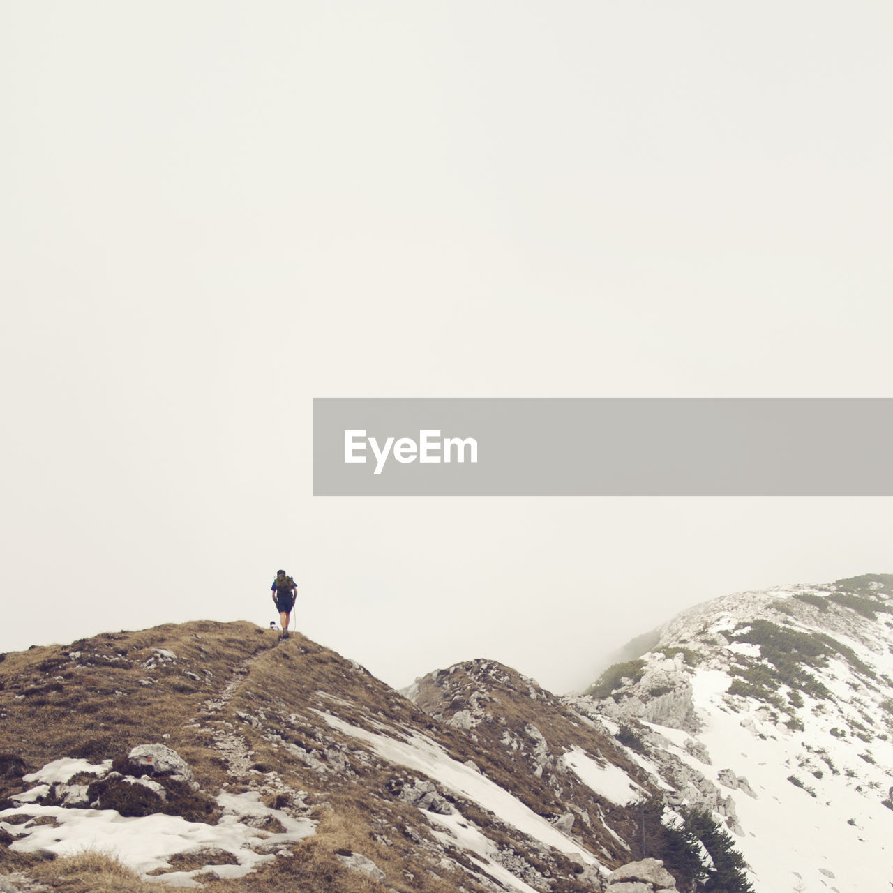 Rear view of person on mountain against clear sky during winter