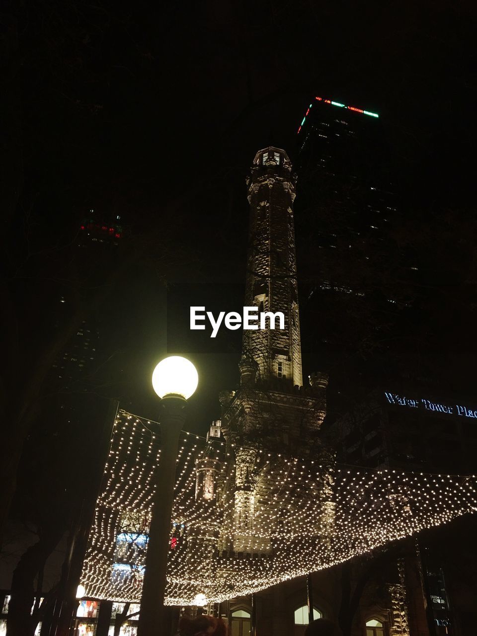 LOW ANGLE VIEW OF ILLUMINATED TOWER AT NIGHT