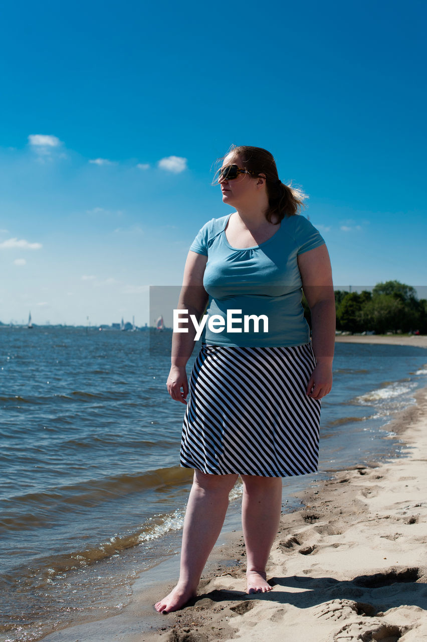 FULL LENGTH OF WOMAN STANDING ON BEACH