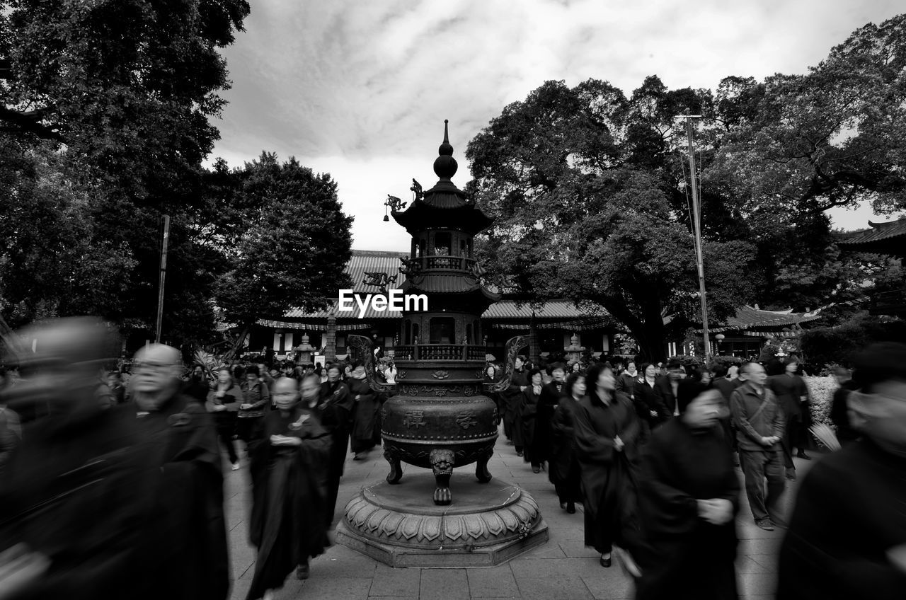 Blurred motion of monks and people on street during ceremony