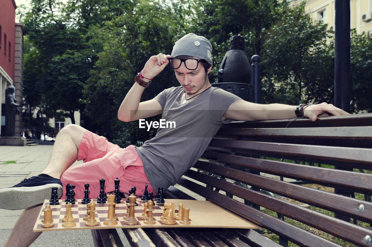 Man playing chess while sitting on bench at park