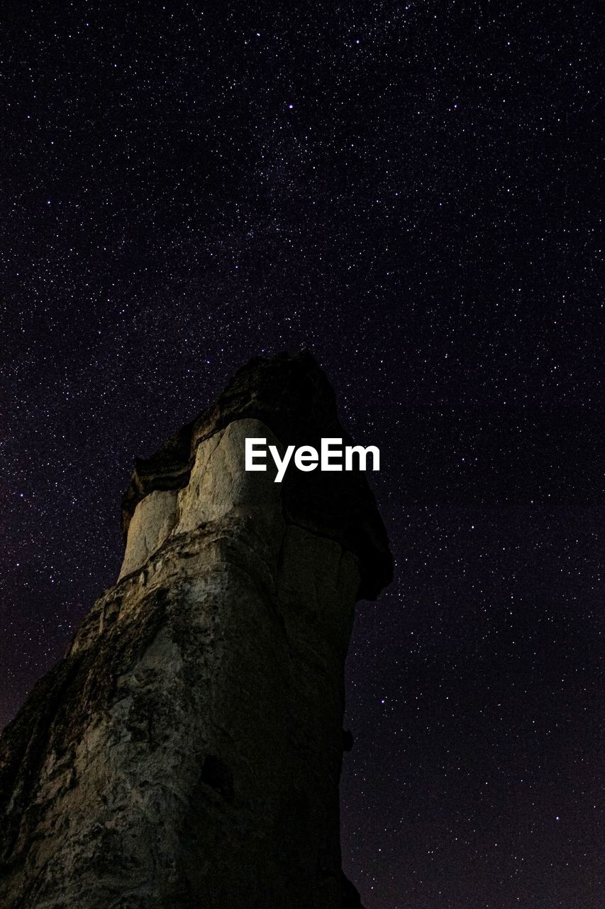 LOW ANGLE VIEW OF ROCK FORMATION AT NIGHT