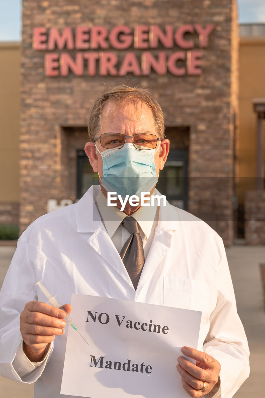 Portrait of doctor wearing mask holding paper with text