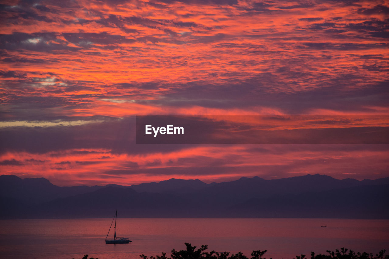 SILHOUETTE SAILBOAT ON SEA AGAINST ORANGE SKY