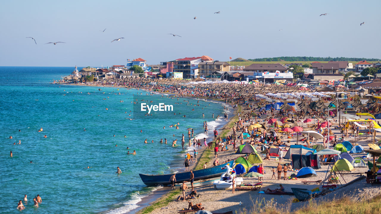 Crowd enjoying at beach against clear sky