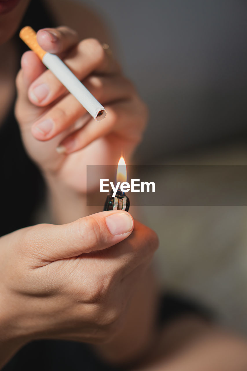 cropped hand holding cigarette lighter on table