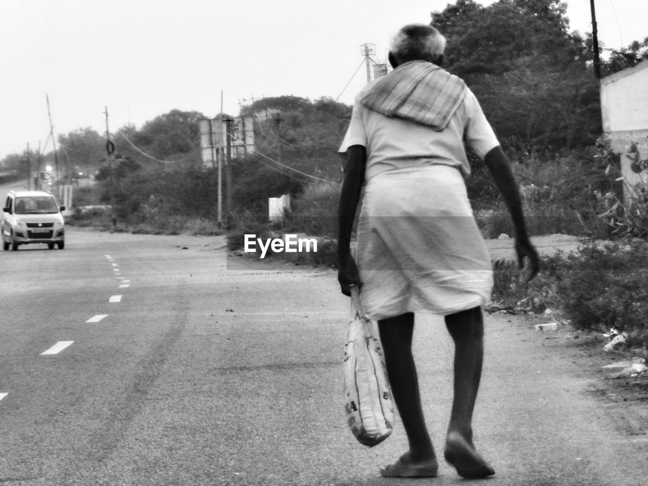 REAR VIEW OF WOMAN STANDING ON ROAD