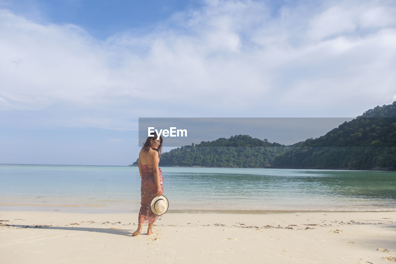 Rear view of woman on beach against blue sky