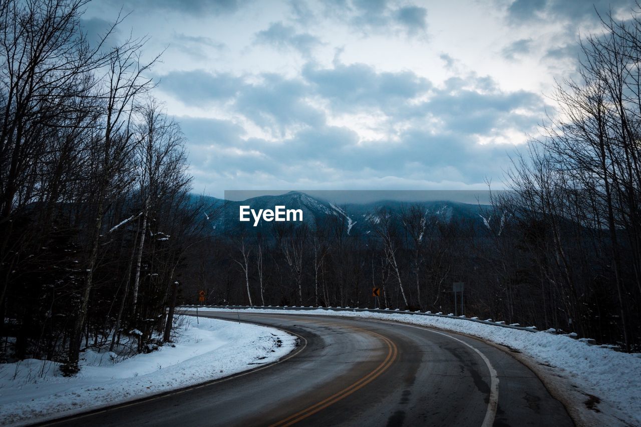 Road amidst trees against sky during winter