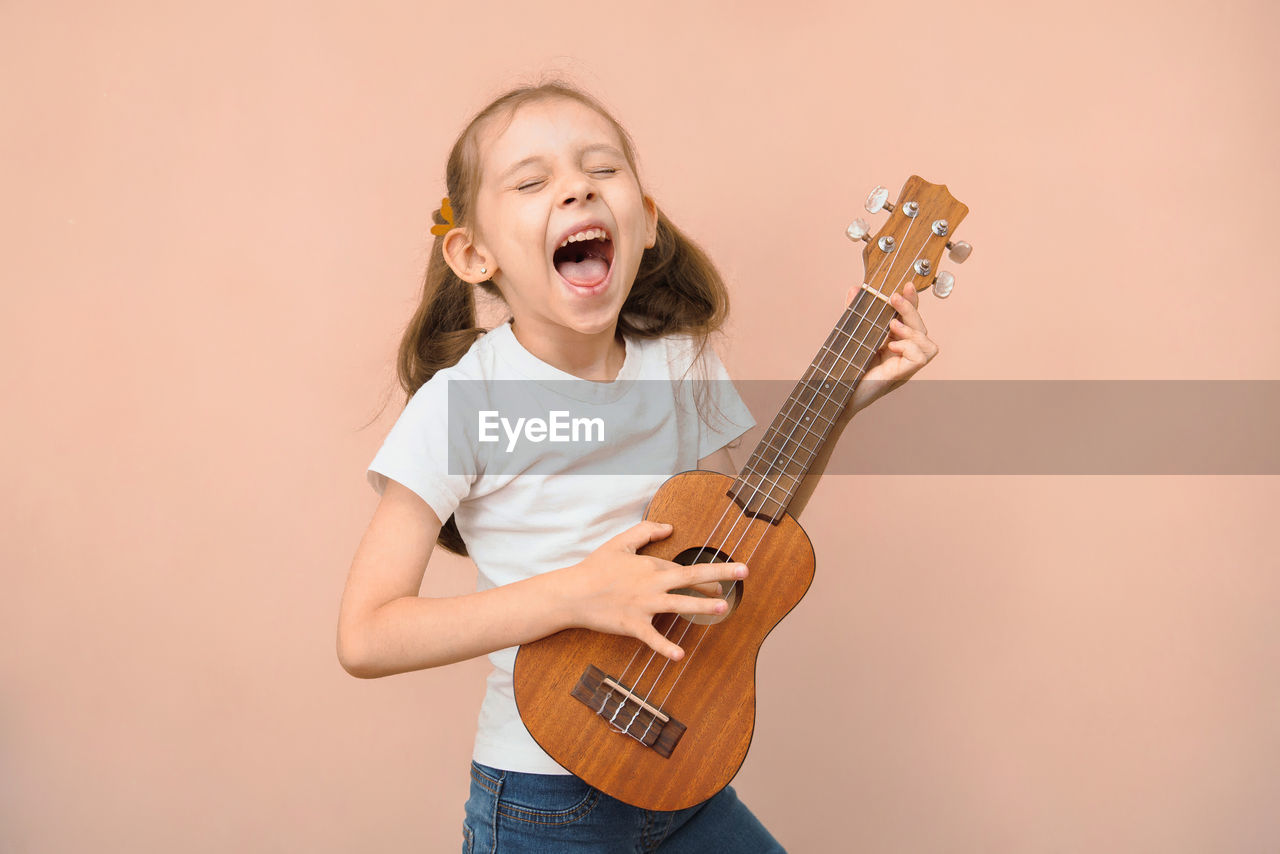 midsection of man playing guitar against wall