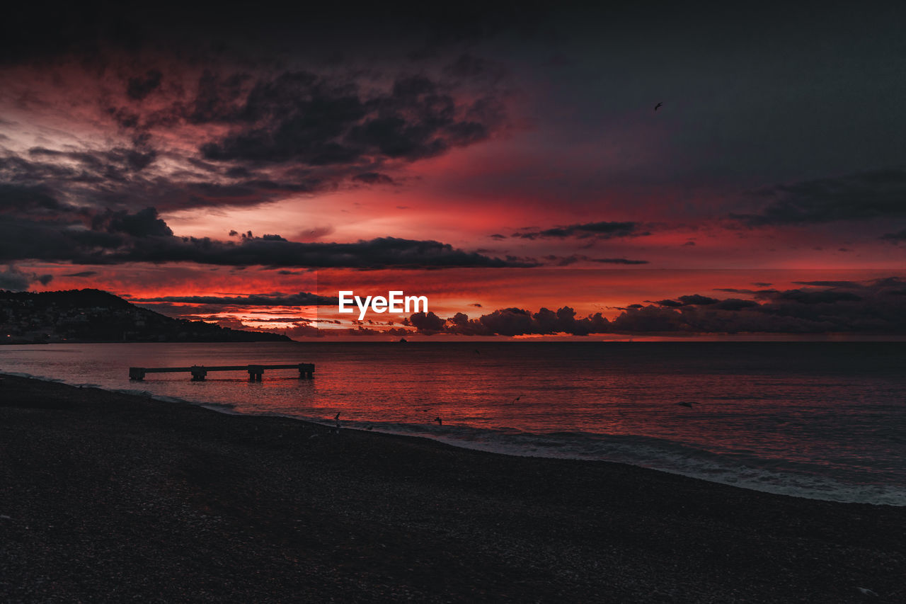 Scenic view of sea against dramatic sky during sunset