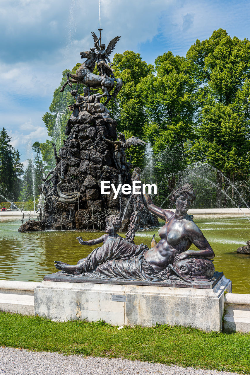 Statues at fountain with trees in background