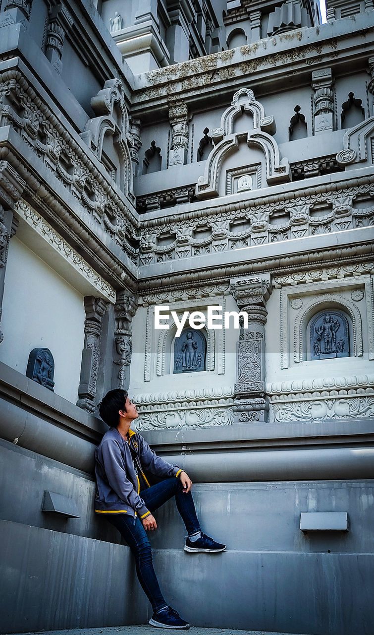 SIDE VIEW OF A MAN SITTING ON BUILDING