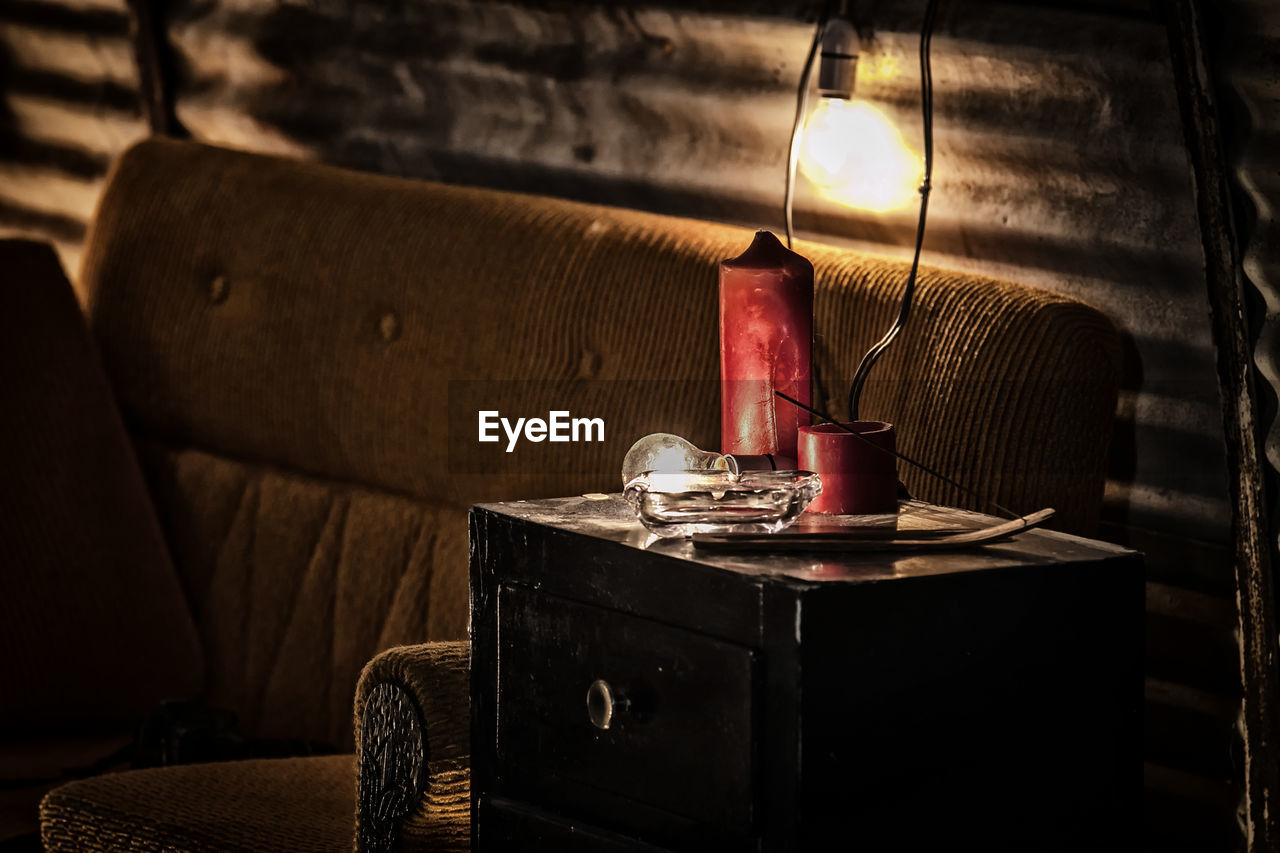 Illuminated light bulb on table by sofa