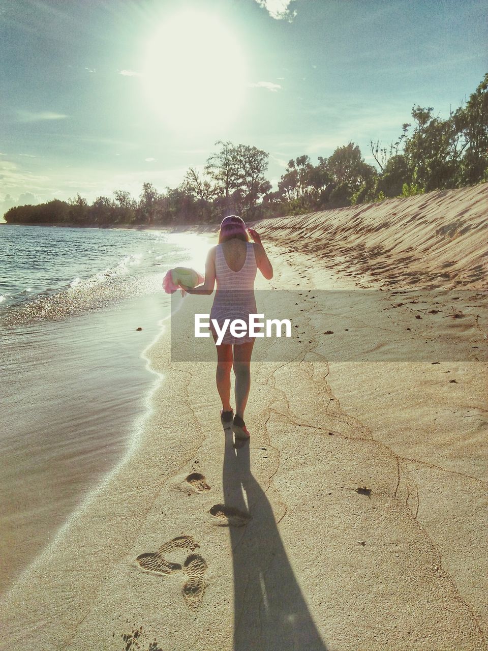 Full length of woman walking on sand at beach against sky