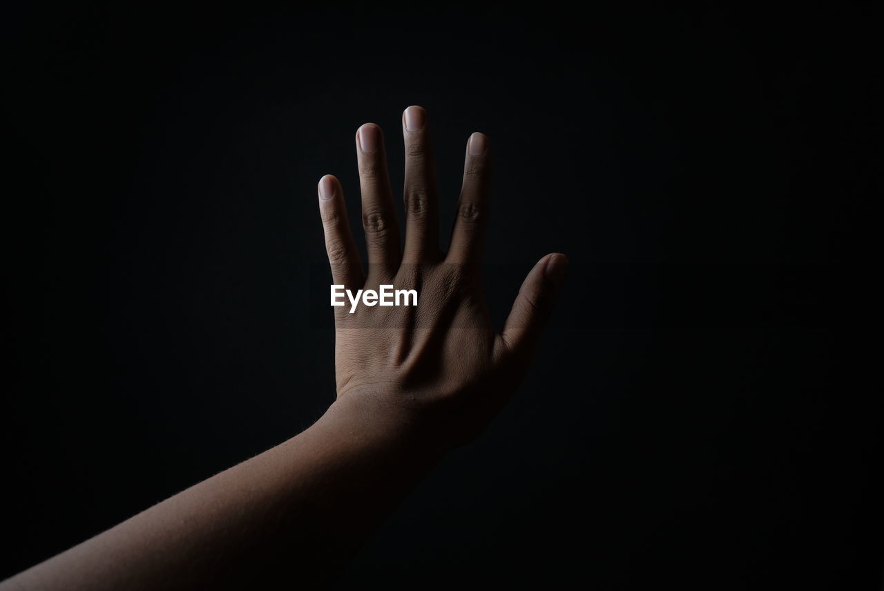 CLOSE-UP OF HAND AGAINST BLACK BACKGROUND