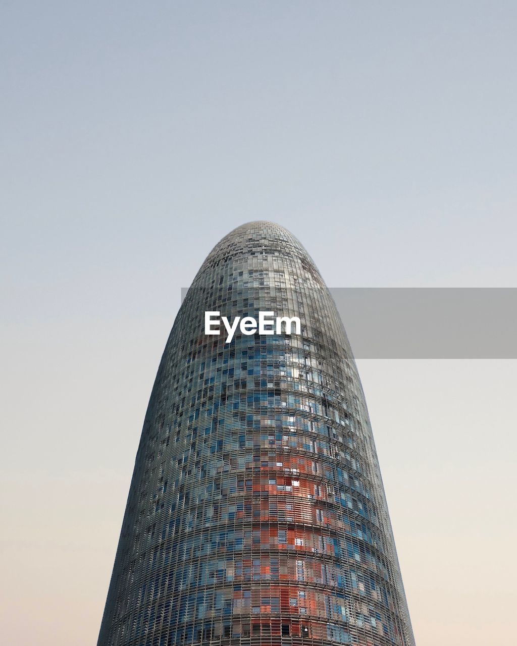 LOW ANGLE VIEW OF MODERN GLASS BUILDING AGAINST CLEAR SKY