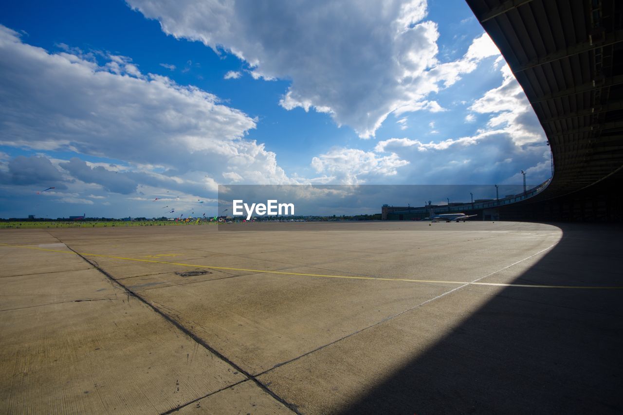 Empty airport runway against cloudy sky