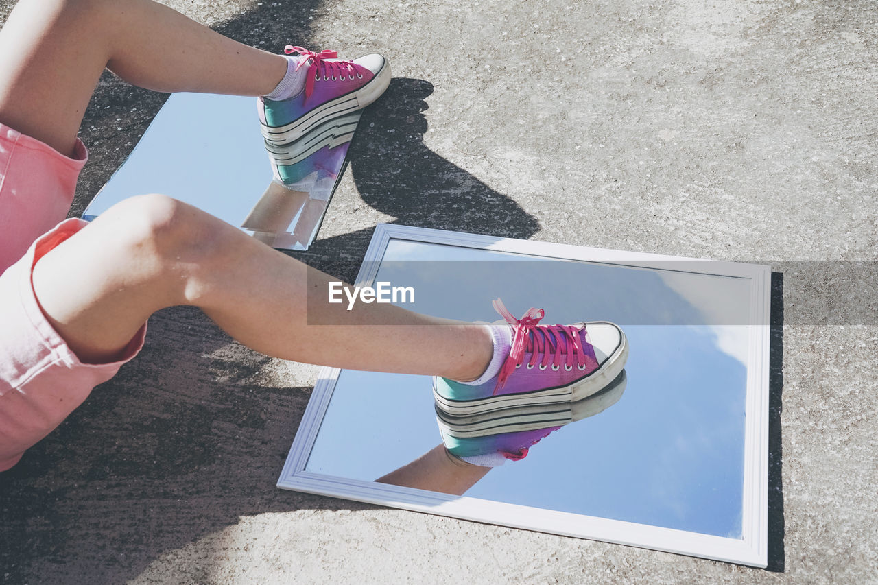 Legs of woman on glass mirror with reflection of sky